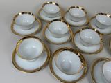 nine cups and saucers sitting on a white table