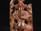 une photo représentant une statue en bois d'un homme assis sur une souche d'arbre