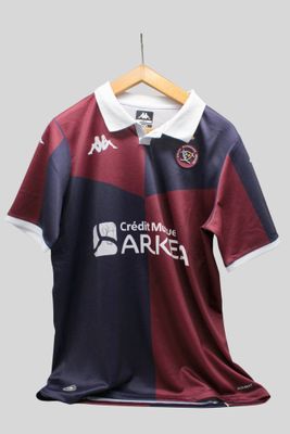 La chemise est bordeaux et bleue, avec un col blanc.