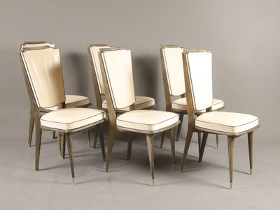 quatre chaises avec des assises en cuir blanc rembourré et un piètement en bois