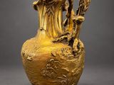 an image of a gold vase with a woman and a bird on it