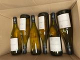 six bottles of white wine in a cardboard box on a table