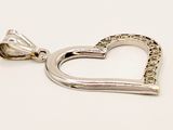 a close up of a heart shaped pendant on a white surface