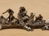 figurines of a group of people sitting on a piece of wood