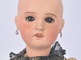a doll with a bald head wearing a dress and earrings