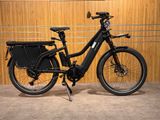 une photo d'un vélo électrique noir garé devant un mur en bois