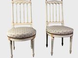 une paire de chaises peintes en blanc, avec des coussins d'assise rembourrés à motifs floraux