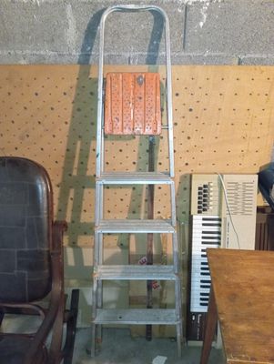 une échelle appuyée contre un mur, à côté d'une chaise
