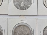six different types of coins in a white box on a white surface