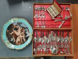 a box with silverware and a plate with a painting on it