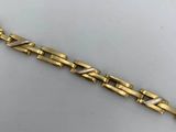 a close up of a gold bracelet on a white surface