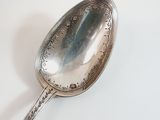 a silver spoon on a white surface with a shadow on it