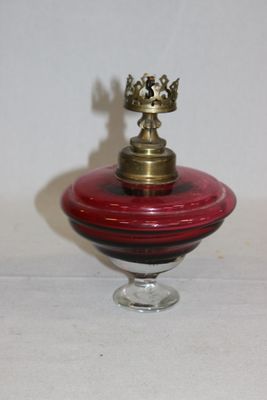 un petit bol en verre rouge avec un couvercle doré, posé sur une table