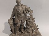 statue représentant un homme avec un chien et un chat, assis sur un rocher