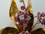 a gold brooch with pink and white stones on it