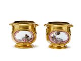 deux vases en or ornés de représentations humaines sur un fond blanc