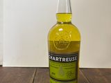 un gros plan sur une bouteille de Chartreuse posée sur une table en bois