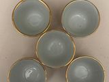 four blue glass bowls with gold rims sitting on a table