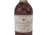 une vieille bouteille de vin posée sur une surface blanche