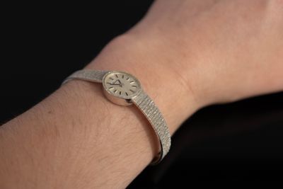 le poignet d'une femme portant une montre, sur fond noir
