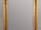 un grand miroir dans un cadre doré, orné d'un motif décoratif