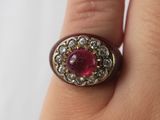an image of a woman ' s hand holding a ring with a red stone