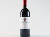 a bottle of red wine sitting on top of a white table