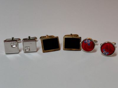 trois paires de boutons de manchette et une paire de boutons de manchette posés sur une surface blanche