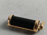 a close up of a black and gold pendant on a white surface