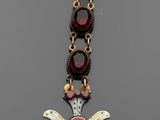 un gros plan sur un collier composé d'or et de grenats