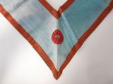 a blue and orange neck piece with a red flower on it