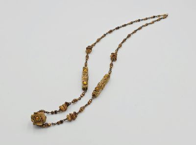 un gros plan d'un long collier de perles posé sur une surface blanche