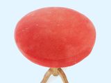 a red stool with a wooden legs on a white surface