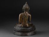 an image of a bronze statue of a person sitting on a pedestal
