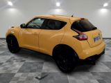 the rear end of a yellow nissan juke suv parked on a checkered floor
