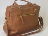a brown leather handbag sitting on top of a white surface
