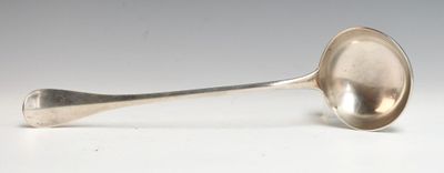 une cuillère en argent ancienne posée sur une table blanche