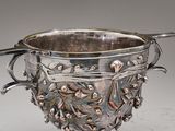 une tasse en argent contenant une cuillère, posée sur une table
