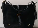Le sac à main noir est posé sur une surface blanche et est muni d'une poignée noire.