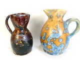 two vases sitting next to each other on a white surface