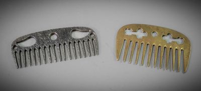 two pieces of metal hair combs sitting on top of a table