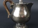 une cafetière en argent avec une poignée en bois sur fond noir