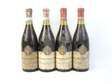 quatre bouteilles de vin sont alignées sur une surface blanche