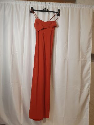 une robe orange suspendue à un rideau blanc devant un rideau blanc