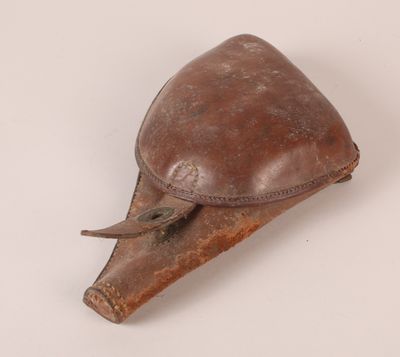 un vieil étui en cuir marron muni d'une poignée en cuir, posé sur une surface blanche