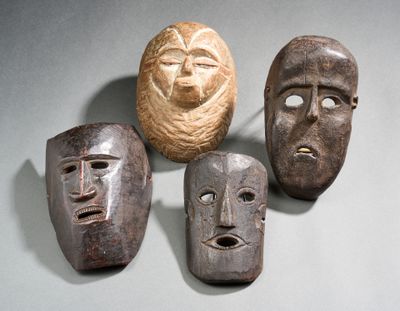 three wooden masks are sitting on a table with a ball