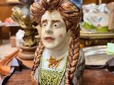 un buste en céramique représentant une femme, posé sur une table