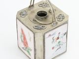 a small metal box with a handle on a white surface
