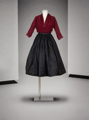 une robe noire et rouge posée sur un mannequin dans une pièce