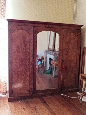 un miroir dans un coin d'une pièce où se trouve une armoire en bois